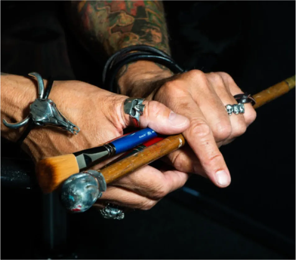 Kevs Hands Holding a Paintbrush Wearing Rock Rings